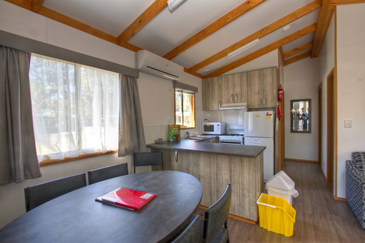 A compact kitchen with a microwave, refrigerator, and wooden cabinets.