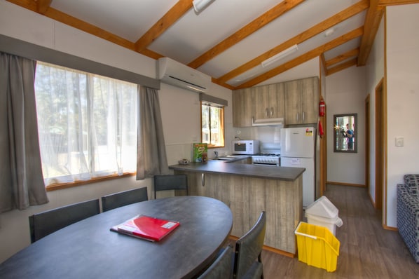 A compact kitchen with a microwave, refrigerator, and wooden cabinets. - Twin Dolphins Holiday Park (Tuncurry)