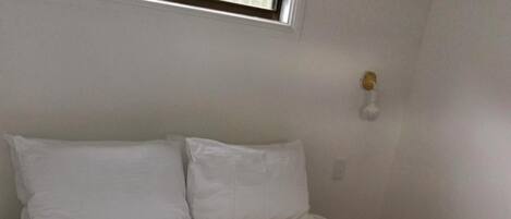 A bed with white linens, a gray striped blanket, and two white towels.