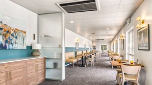 Un restaurante moderno con una barra alargada, asientos acolchados y obras enmarcadas en las paredes.