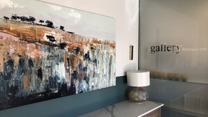 Un interior moderno con un cuadro abstracto de gran tamaño, una encimera de mármol y una pared de vidrio con el texto 'gallery Restaurant'.