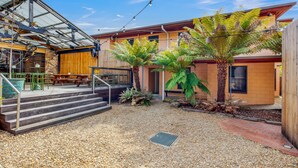 A building with a patio area featuring steps, outdoor seating, and a gravel ground.
