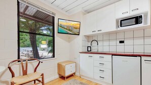 A modern kitchen with white cabinets, a microwave, a sink, and a window with a view of a cityscape.