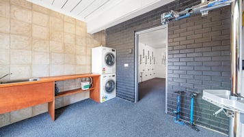 Ein Waschraum mit Waschmaschine, Spüle und Sitzbank.