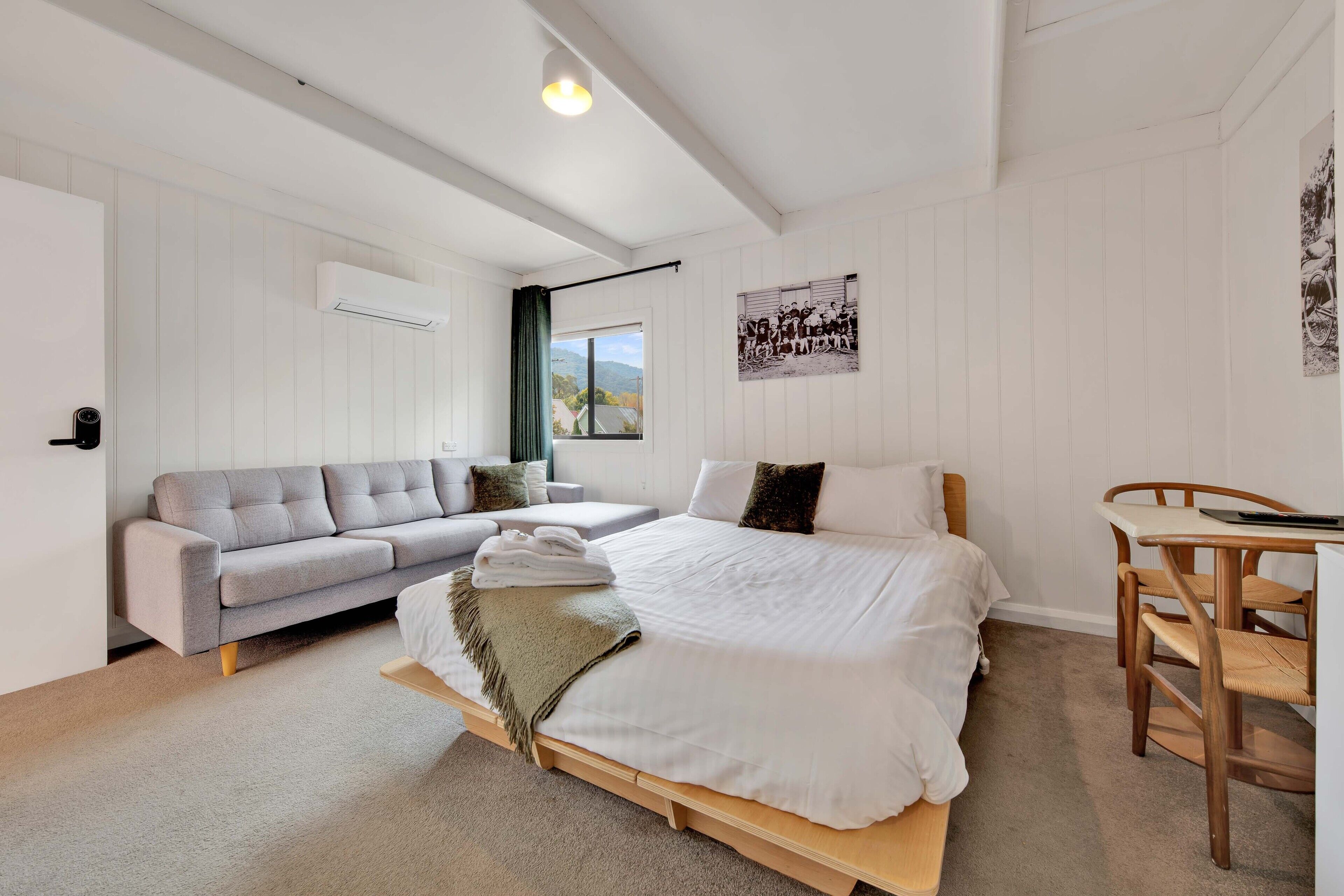Ein Schlafzimmer mit Bett, Sofa, Esstisch und Fenster mit Aussicht.