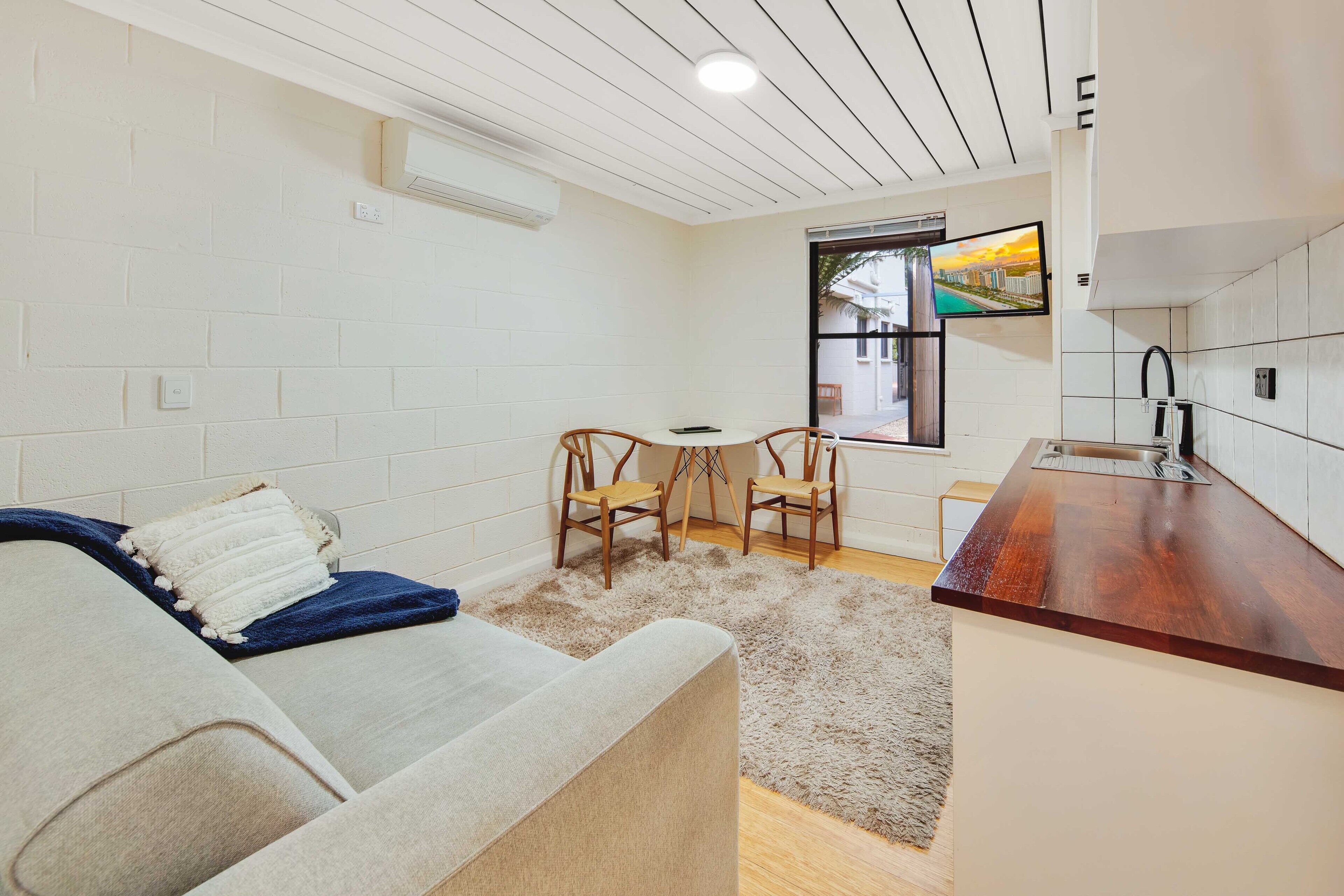 A compact living space with a kitchenette, a sofa, a small dining table, and two chairs.