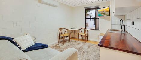 A compact living space with a kitchenette, a sofa, a small dining table, and two chairs.