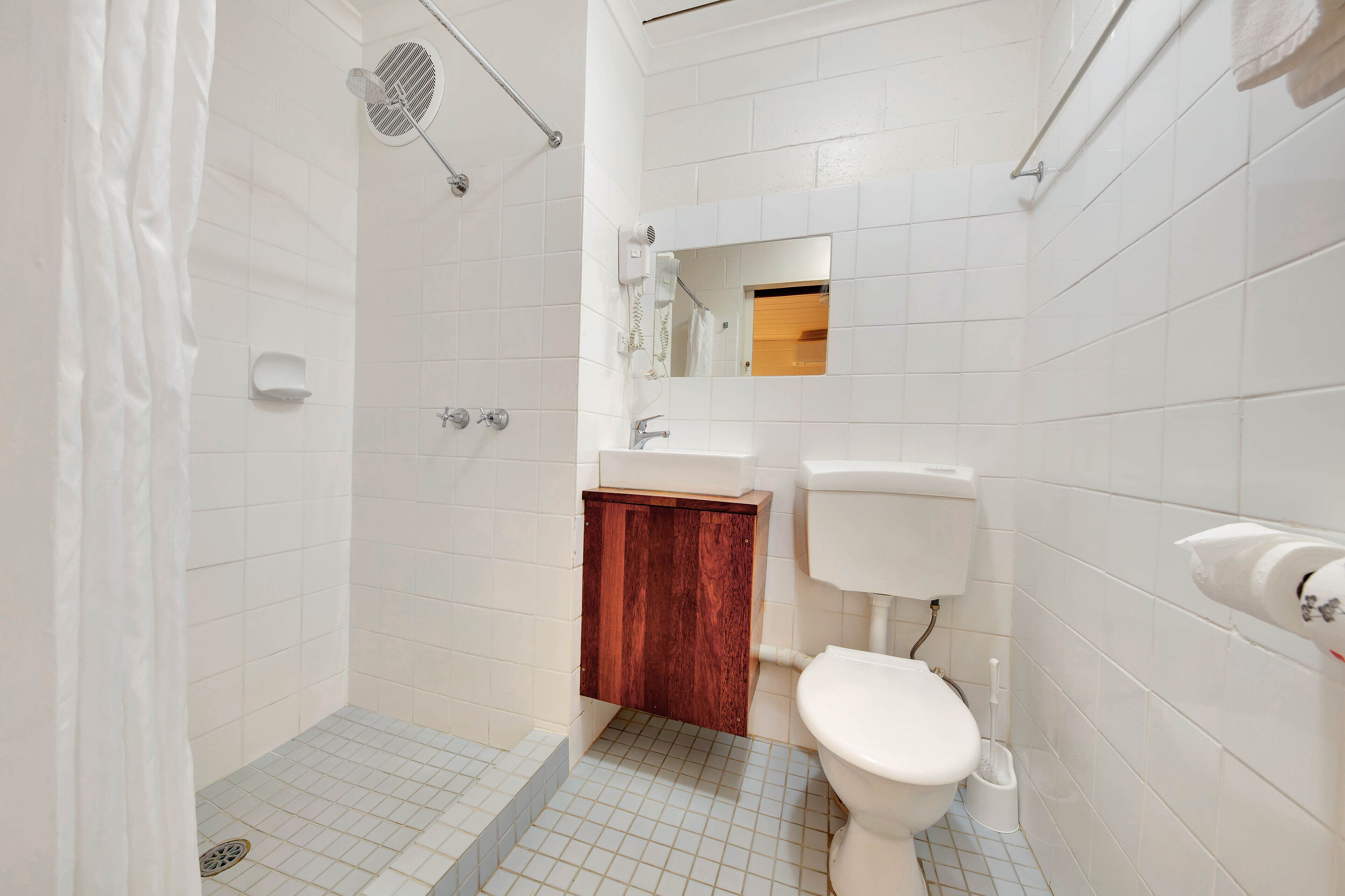 A bathroom with a shower, toilet, sink, and mirror.