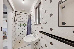 A bathroom with a white sink, a shower, and a window.
