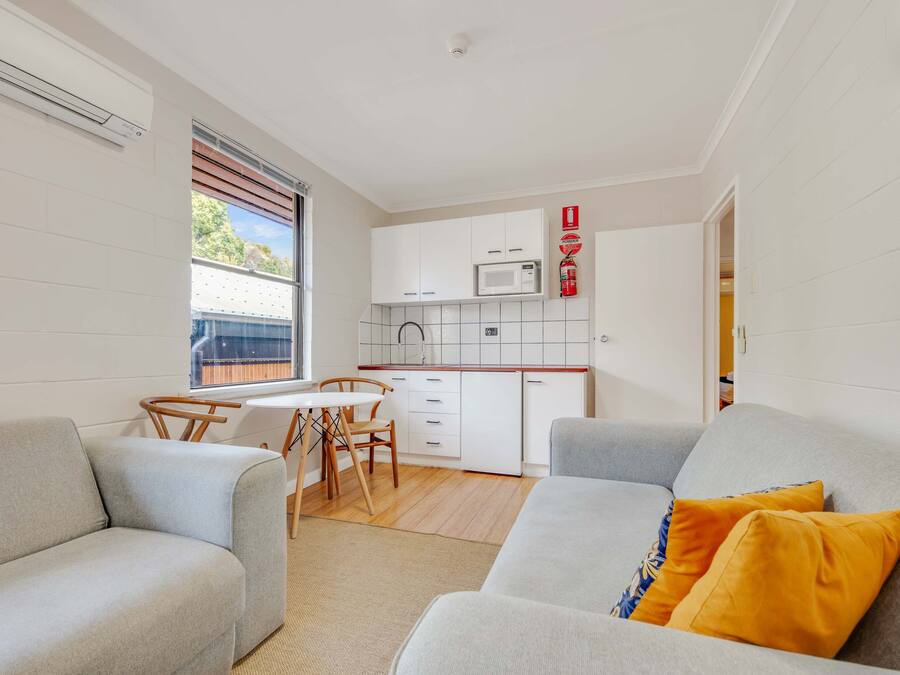 Ett kompakt bostadsutrymme med ett litet kök, en matplats och en sittgrupp med en soffa och två fåtöljer.