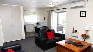 A compact living space with a kitchenette, a dining area, and a seating area with a coffee table. - Westwood Motor Inn (Armidale)