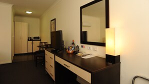 A hotel room with a dark wooden desk, a flat-screen TV, a microwave, a chair, and a large mirror. - Horsham Mid City Court Motel (Horsham)
