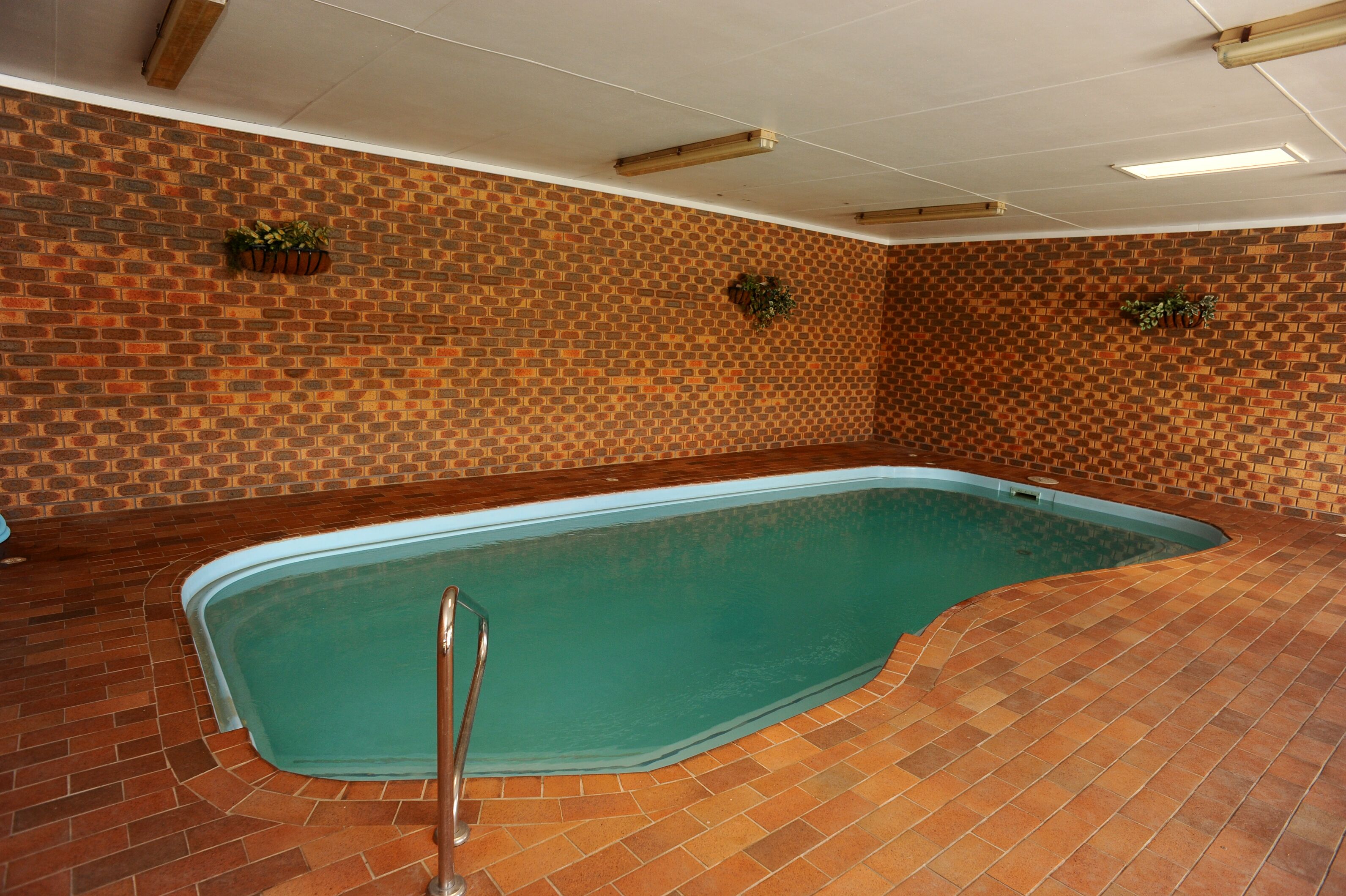 An indoor swimming pool with a brick wall and tiled floor.
