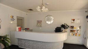 A reception desk with a modern design, a sign for 'Golden Chain Platinum', and a bulletin board with various notices. - Horsham Mid City Court Motel (Horsham)