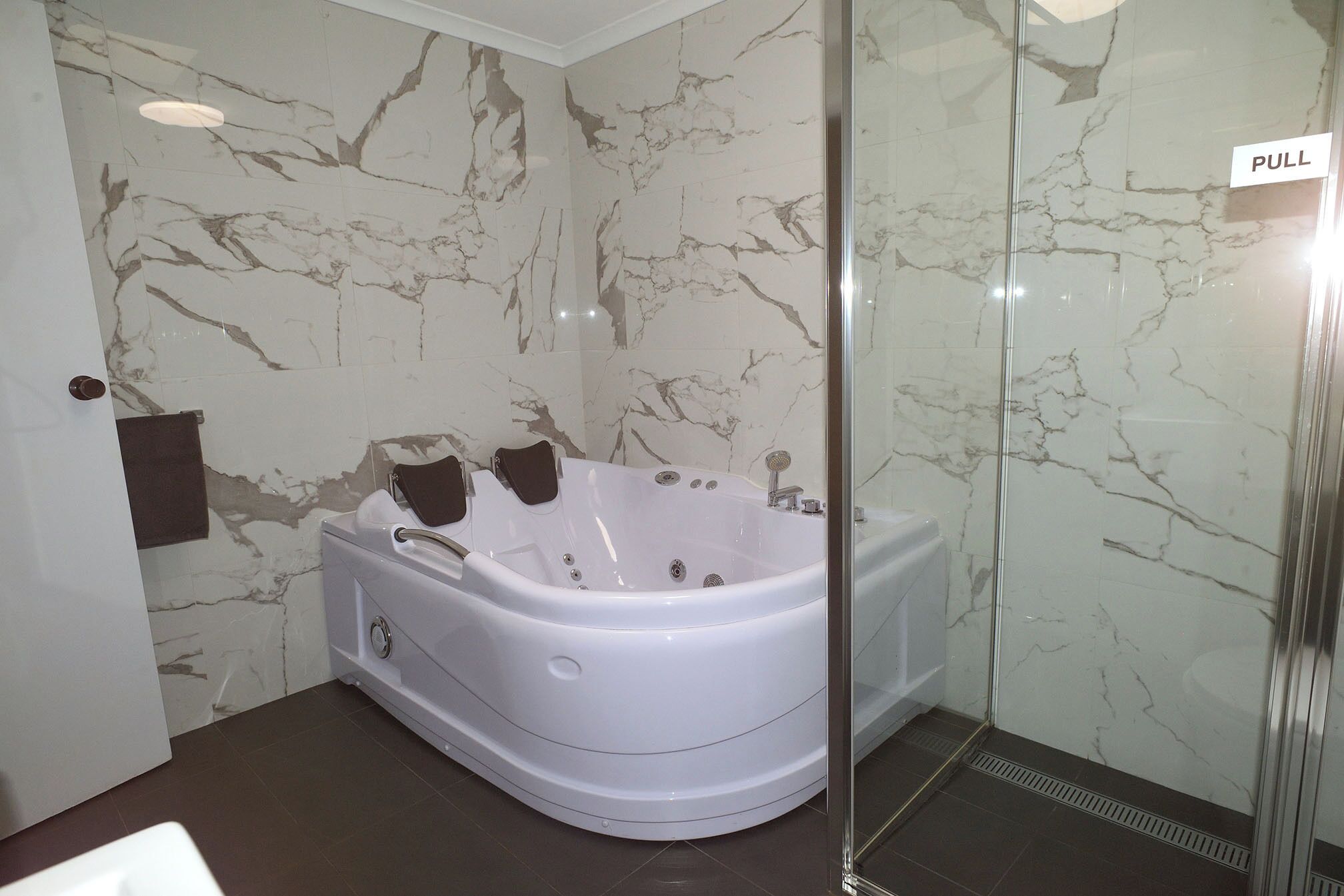 Un baño con pared de mármol, una bañera, ducha y un perchero para toallas.