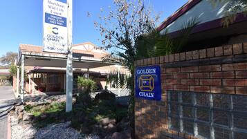 A building with a sign for Horsham Mid City Court, a Golden Chain Platinum sign, and a brick wall with a window.