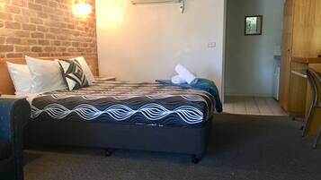 Hotelkamer met een bakstenen muur, een bed met behang, een nachtkastje en een wandairconditioner.