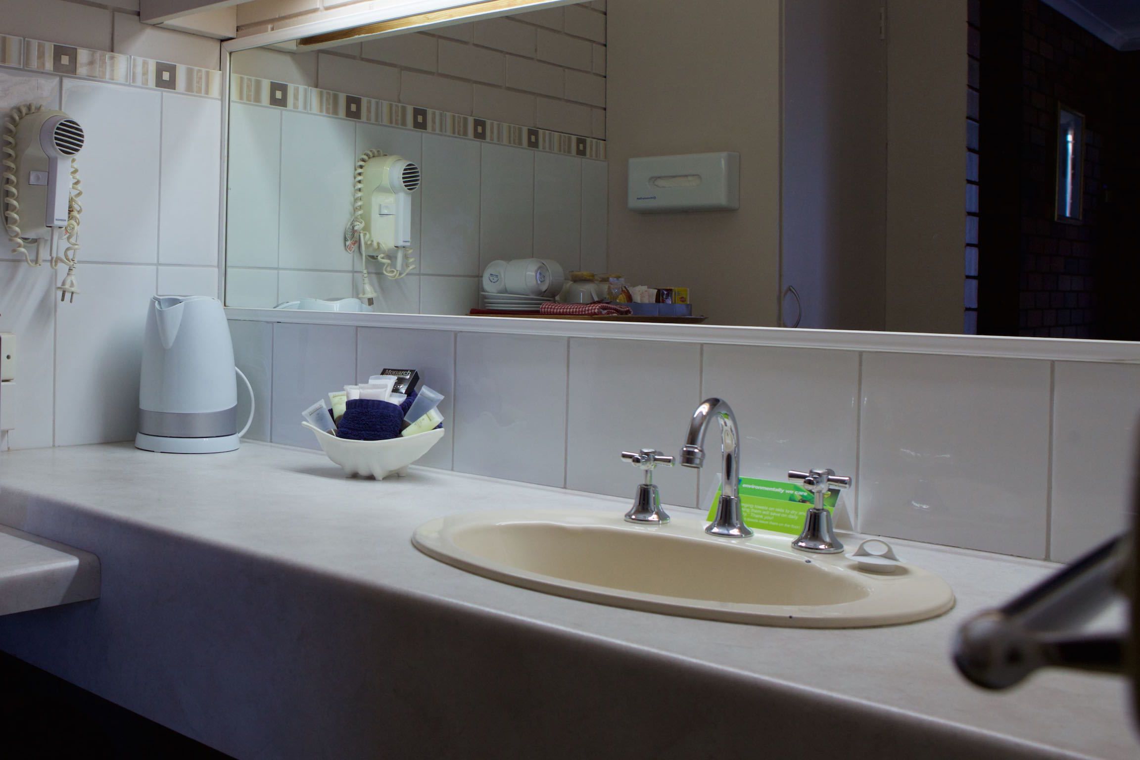 Un baño con lavamanos, espejo y secador de pelo.