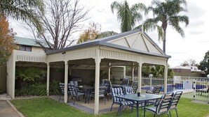 Une terrasse extérieure couverte avec une piscine, entourée de chaises et de tables.