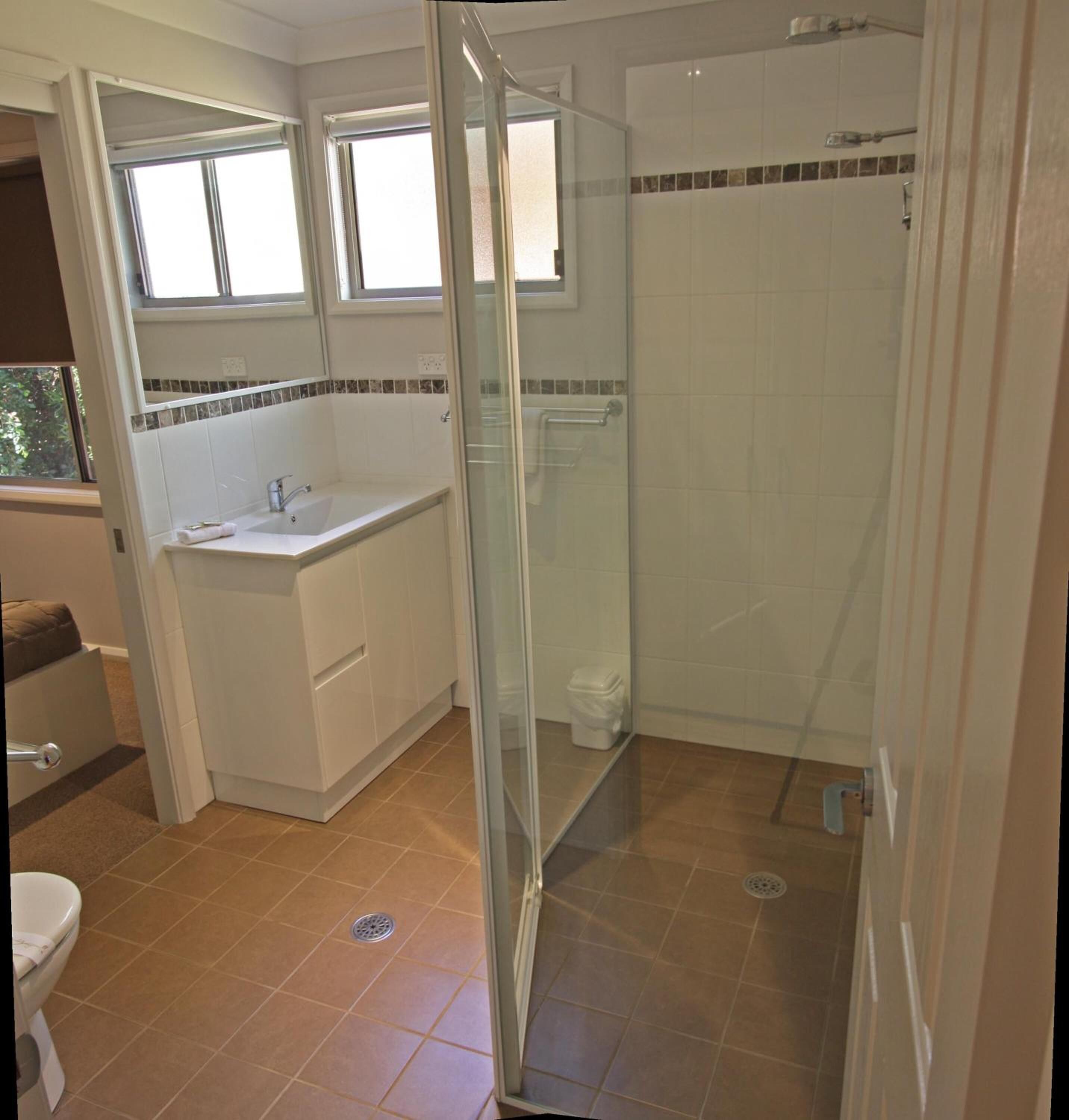 A bathroom with a glass-enclosed shower, a sink, and a toilet.