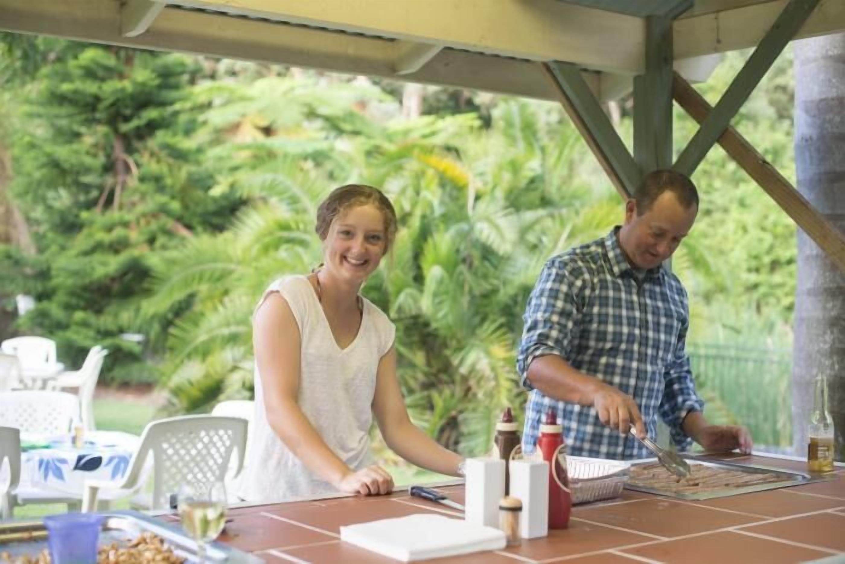 An outdoor dining area with a table set for two, surrounded by lush greenery.