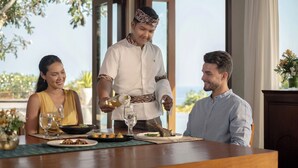 Un tavolo imbandito con piatti di cibo, bicchieri e un cameriere che serve un piatto.