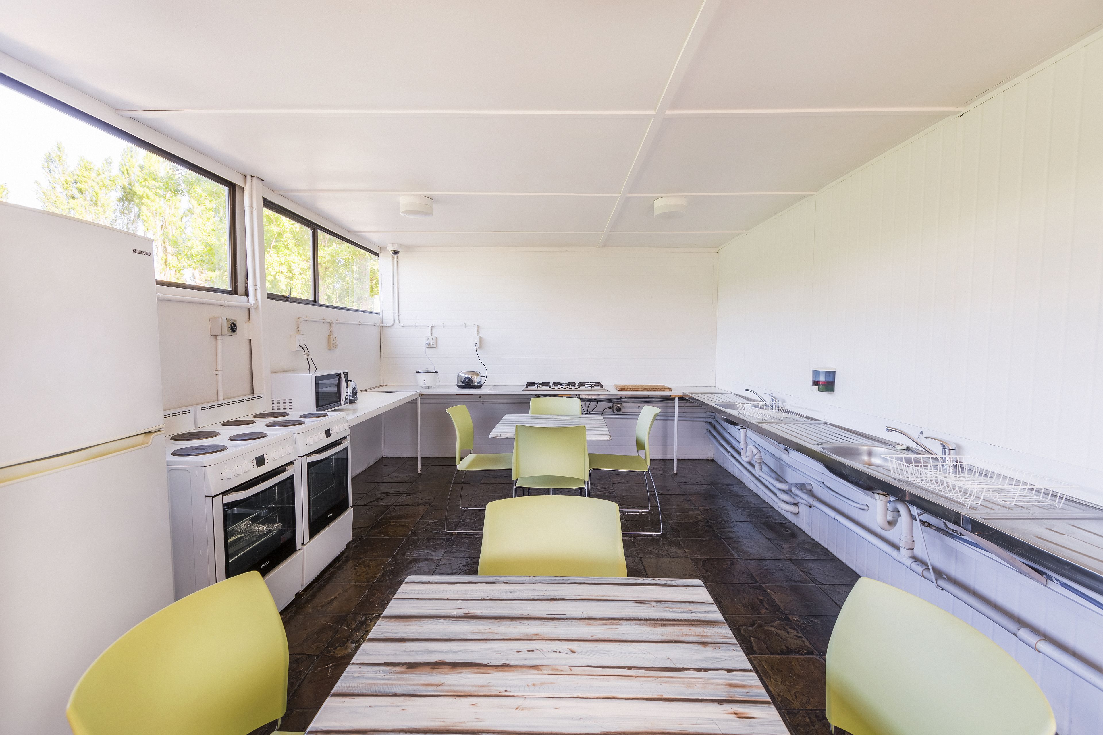 Una cocina moderna con electrodomésticos blancos, una encimera amplia y sillas amarillas.