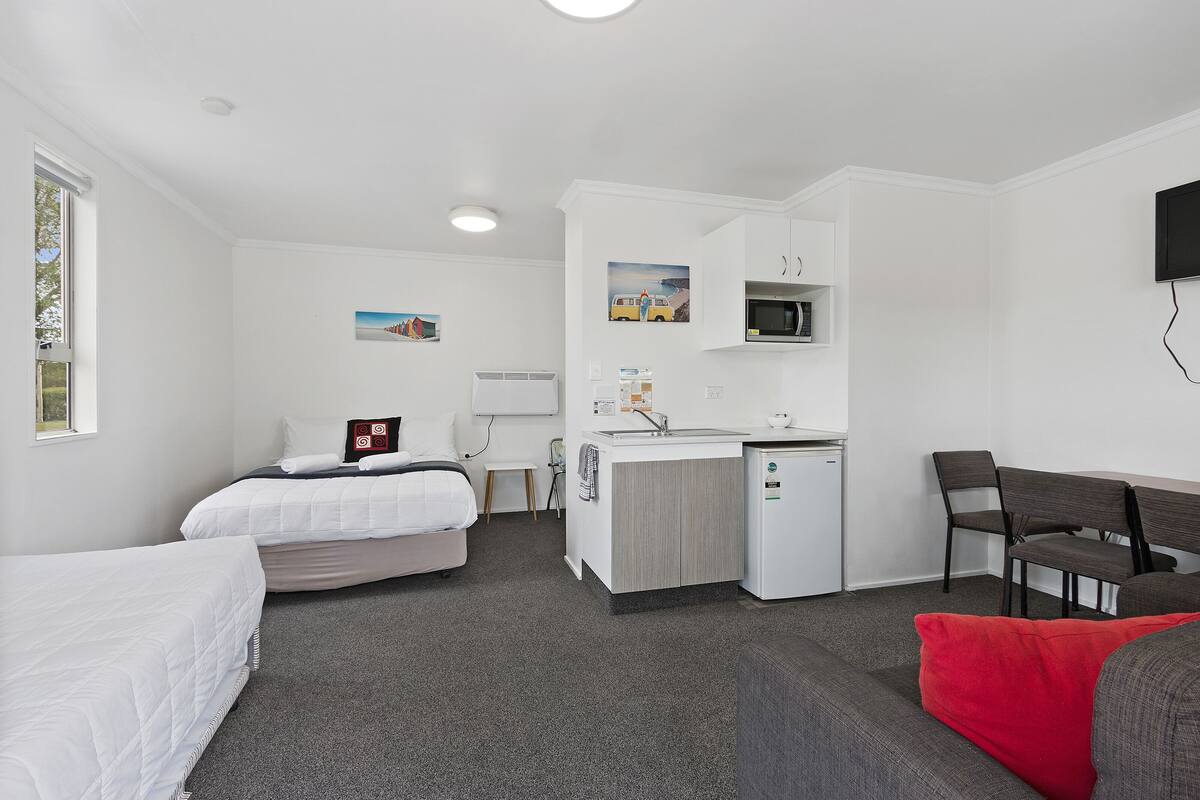 Une chambre d’hôtel avec deux lits, une kitchenette, un coin repas et un téléviseur.