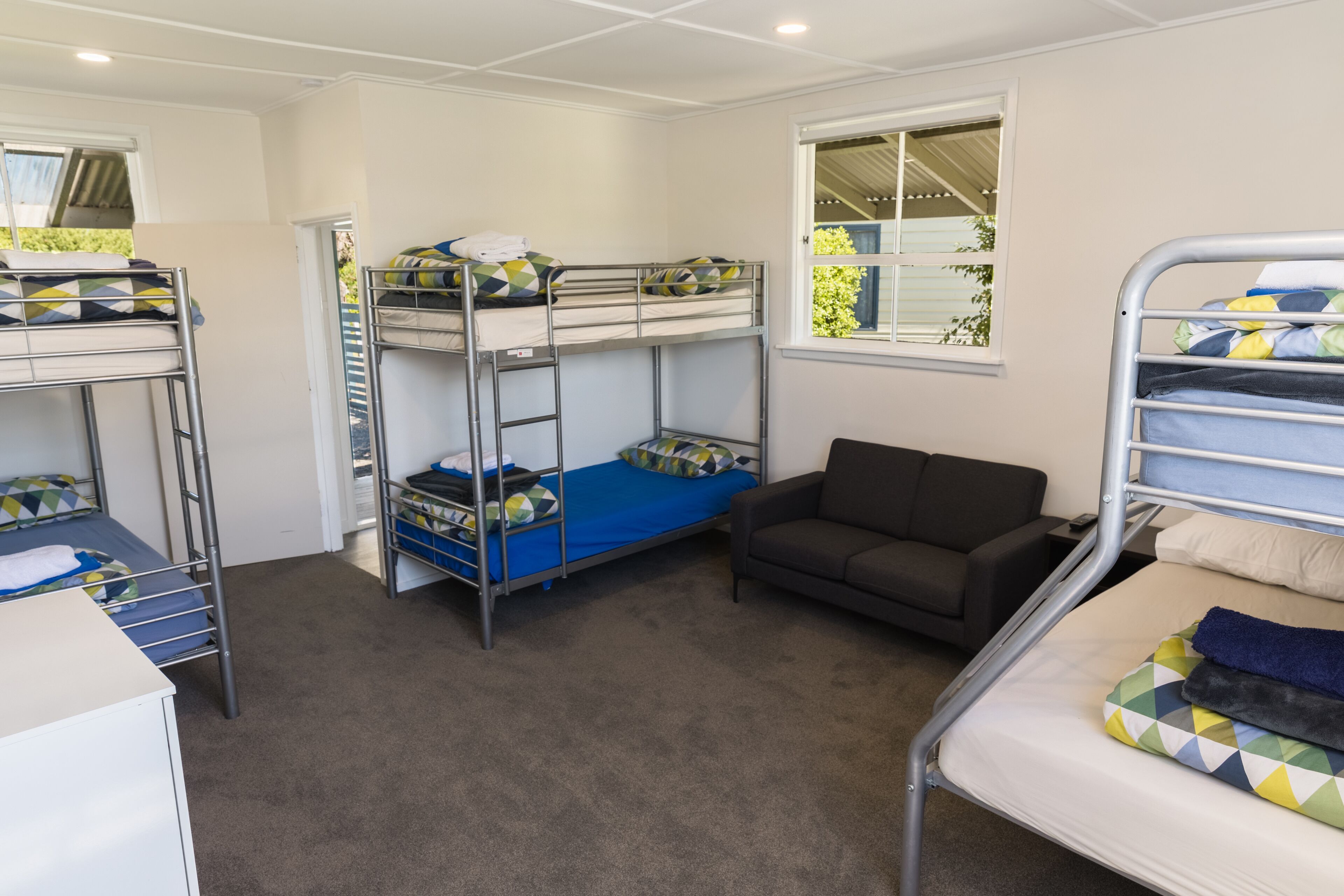 Un dormitorio con literas, un sofá y una ventana con vistas al verdor.