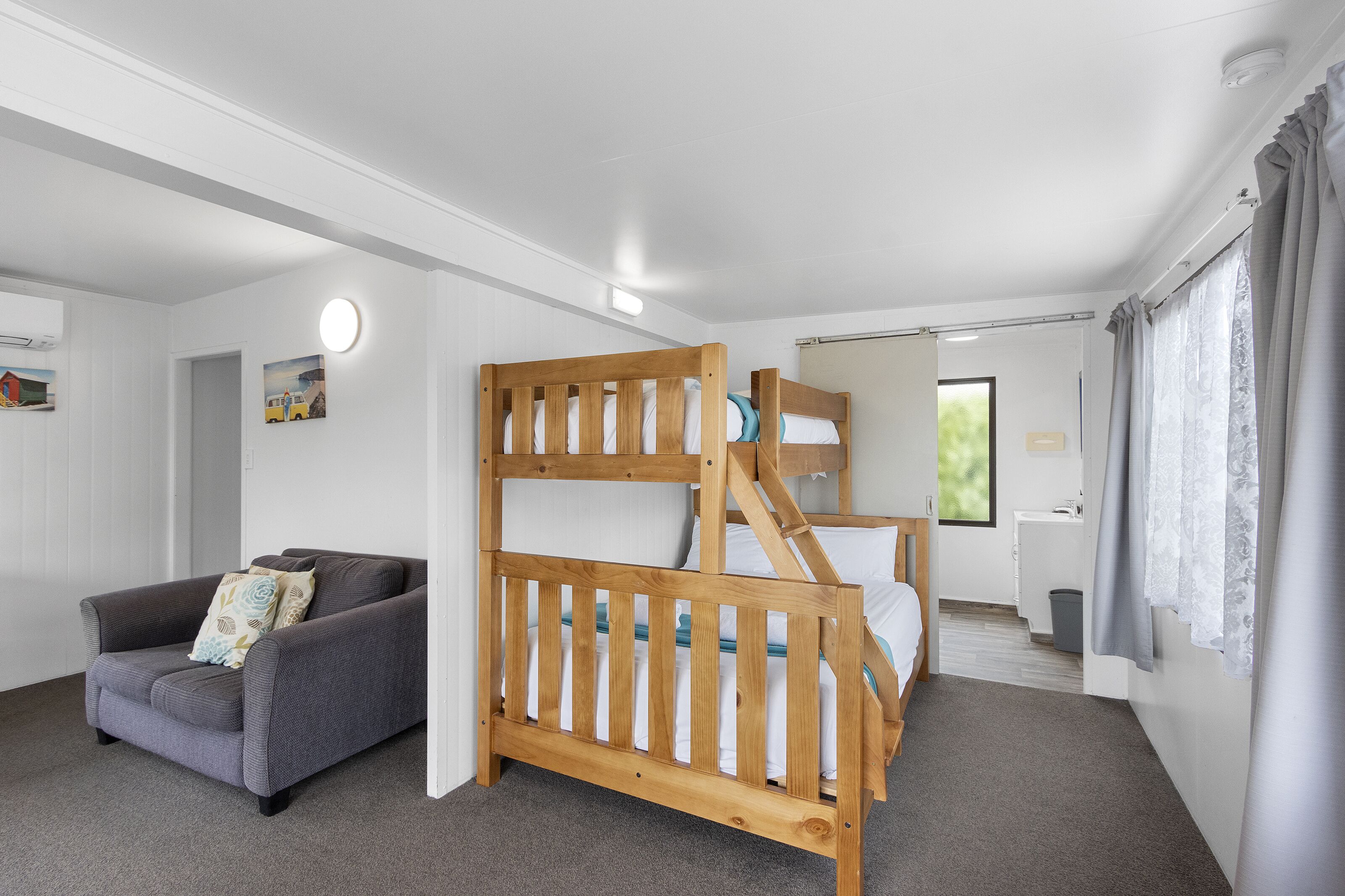 Une chambre avec un lit superposé, un canapé et un petit bureau.