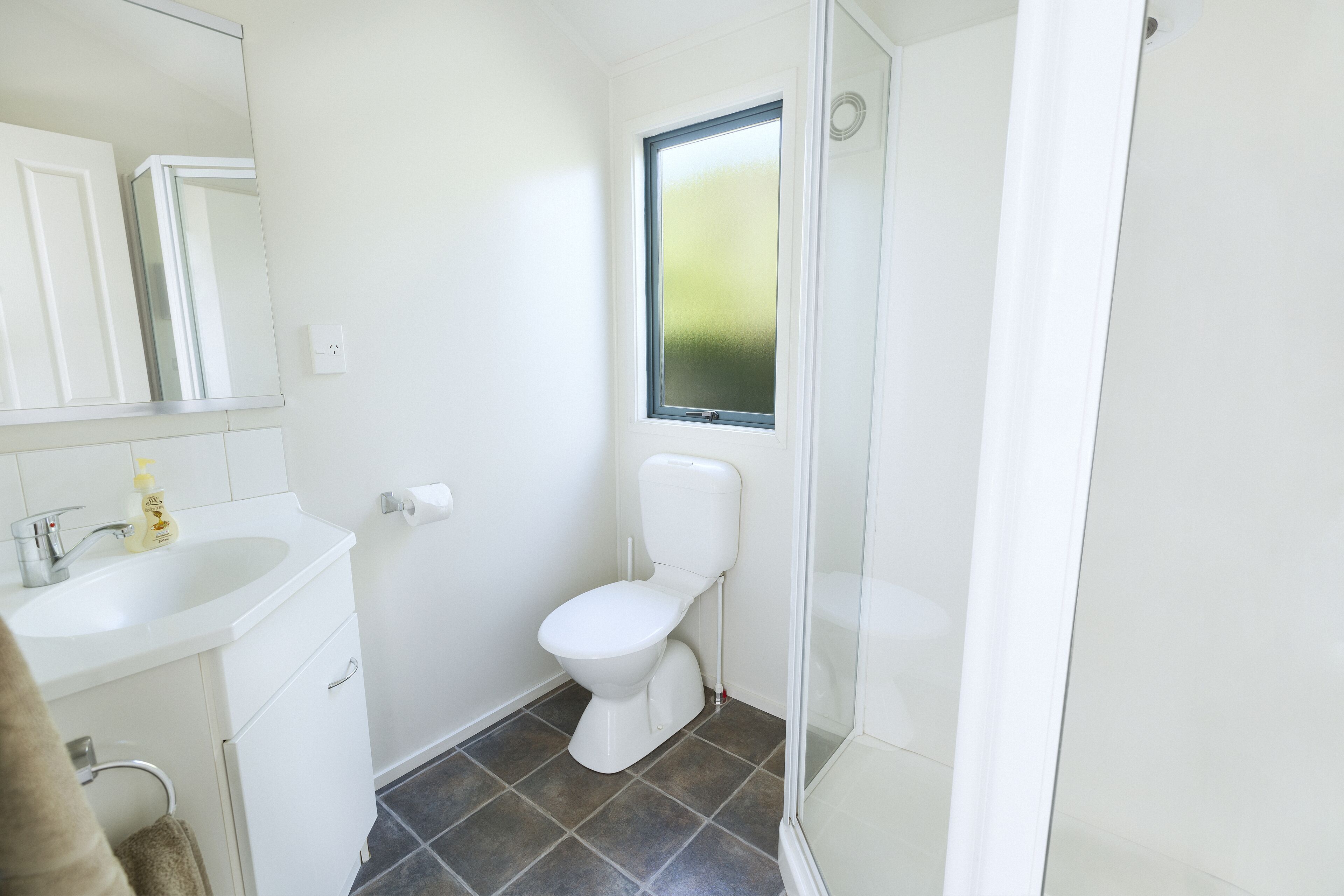 A small, clean bathroom with a toilet, sink, and a window.