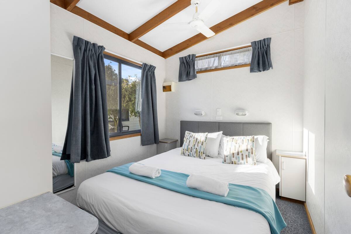 Une chambre d’hôtel moderne, dotée d’un grand lit, d’un bureau et d’une fenêtre avec des rideaux.