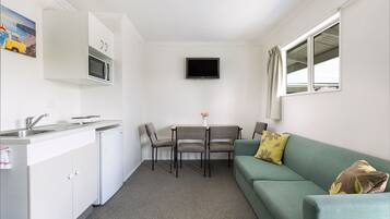 A compact kitchen with a microwave, a sink, and a dining area with chairs and a table.
