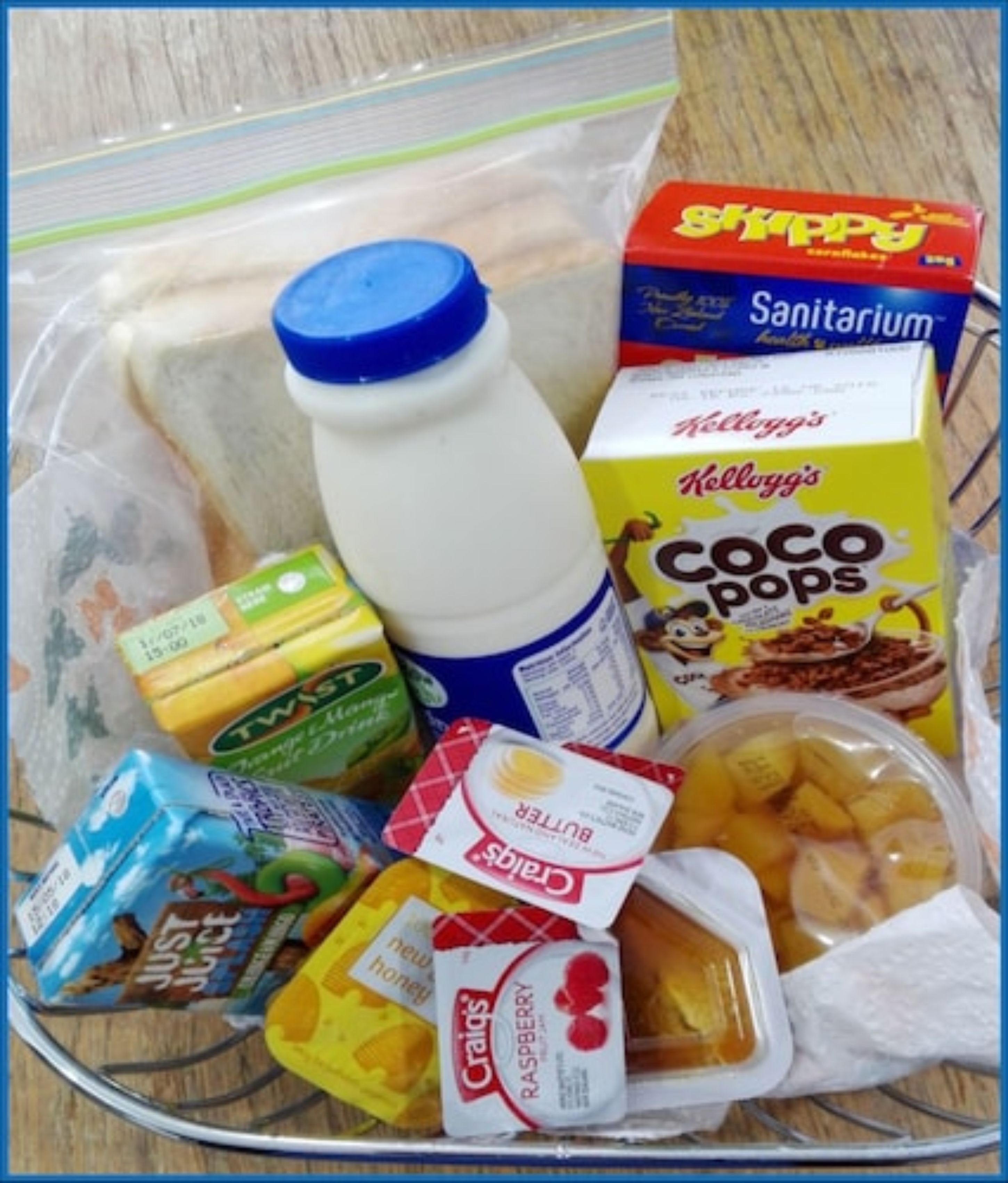 Diversos alimentos como cereal, leche y snacks en un recipiente de plástico transparente.