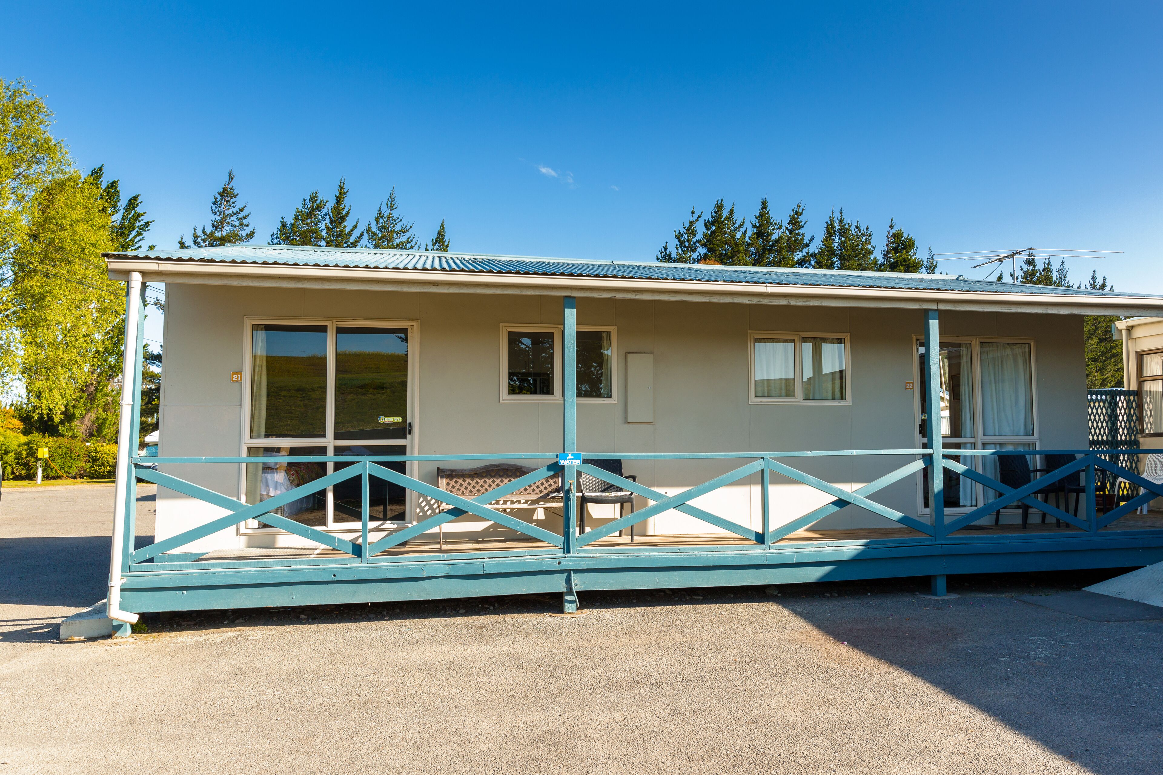 A single-story mobile home with a porch and a covered outdoor seating area.