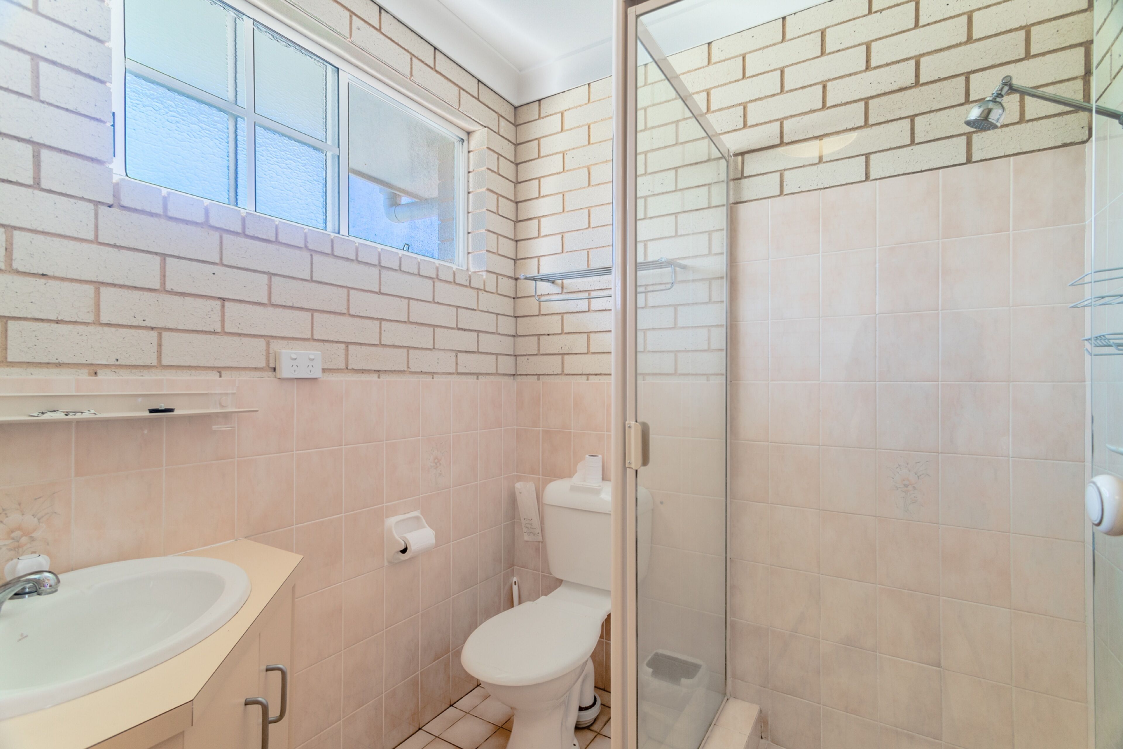 A bathroom with a toilet, sink, and shower area.