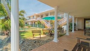 A covered outdoor area with a patio, benches, a staircase, and a building in the background. - Santa Fe Motel & Holiday Units (Lennox Head)