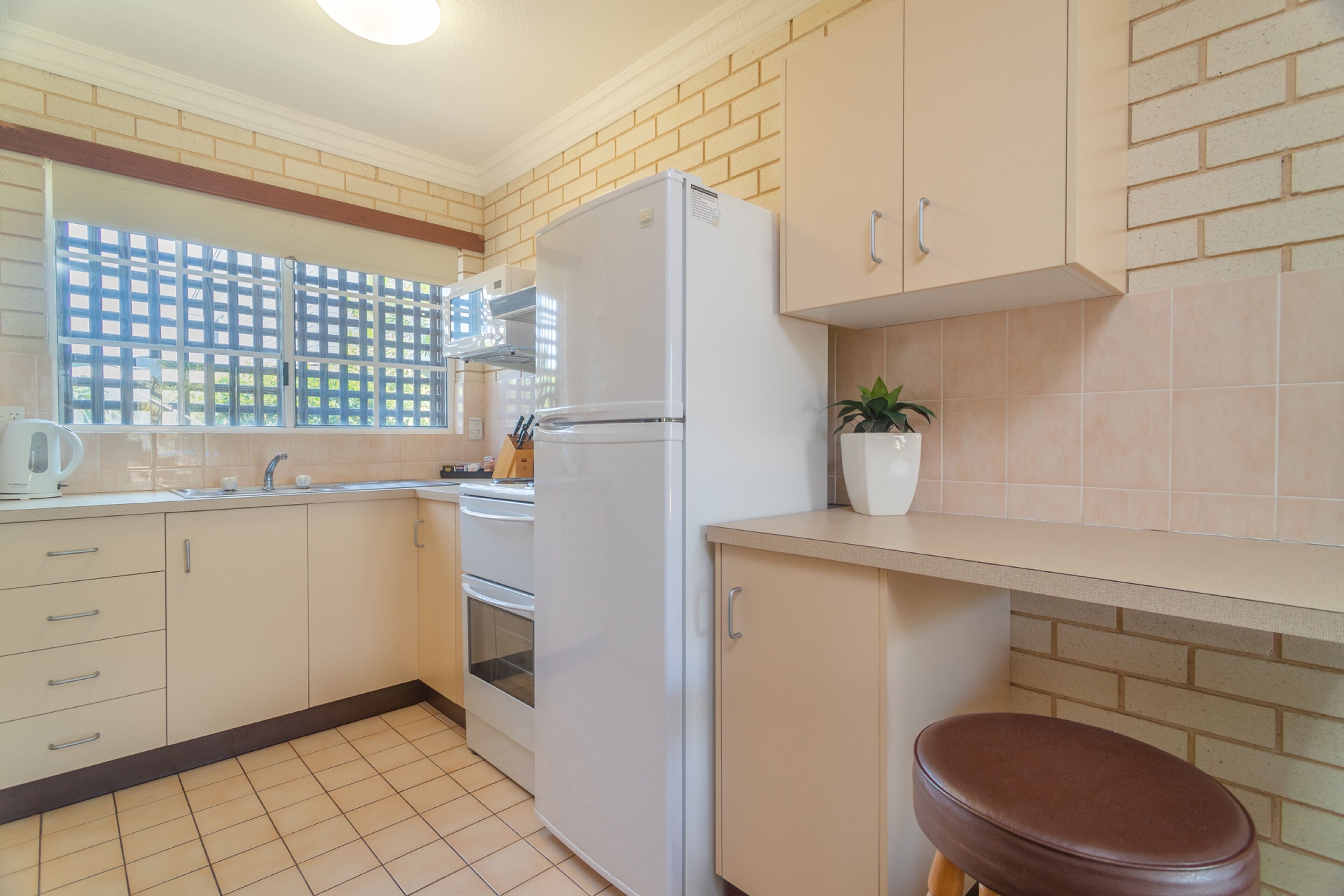 A kitchen with a refrigerator, stove, sink, and cabinets.