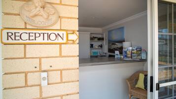 A reception area with a 'RECEPTION' sign, a welcome angel sculpture, and a counter with various items.