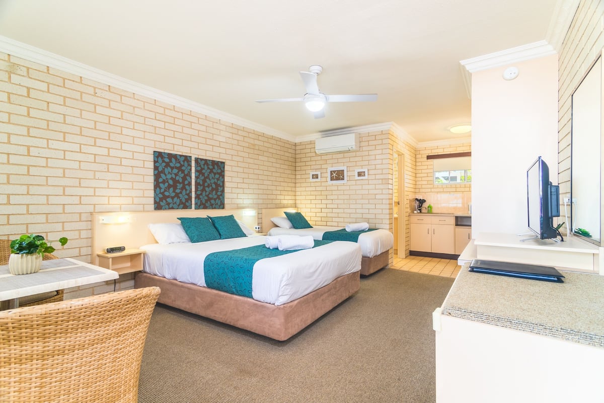 A hotel room with two beds, a dining area, and a kitchenette.