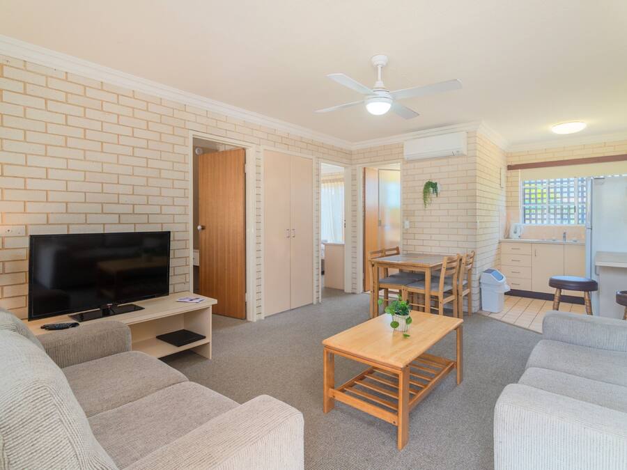 A living room with a TV, sofas, a wooden table, and a ceiling fan.