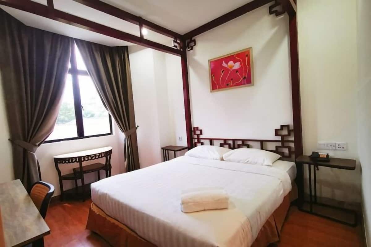 A bedroom with a four-poster bed, a desk, and a chair.