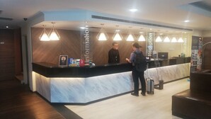 A reception desk with a marble counter, multiple pendant lights, and a digital screen.