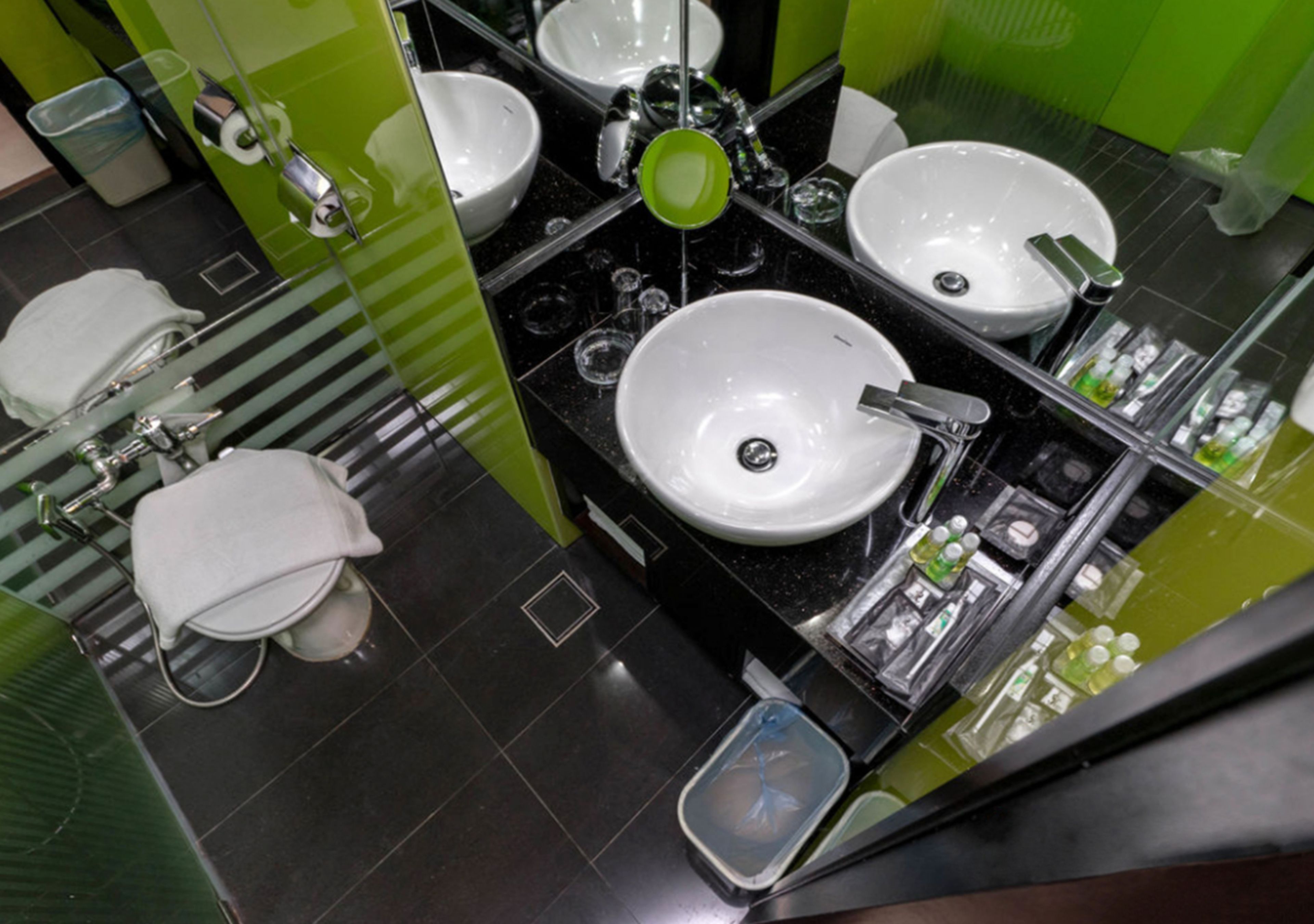 A modern bathroom with three sinks, a toilet, and a mirror.