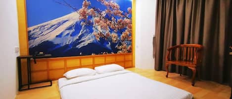A hotel room with a large bed, a wooden chair, and a wall mural of a mountain and cherry blossoms.
