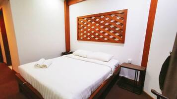 A hotel room with a bed, a wooden headboard, a nightstand, and a chair.