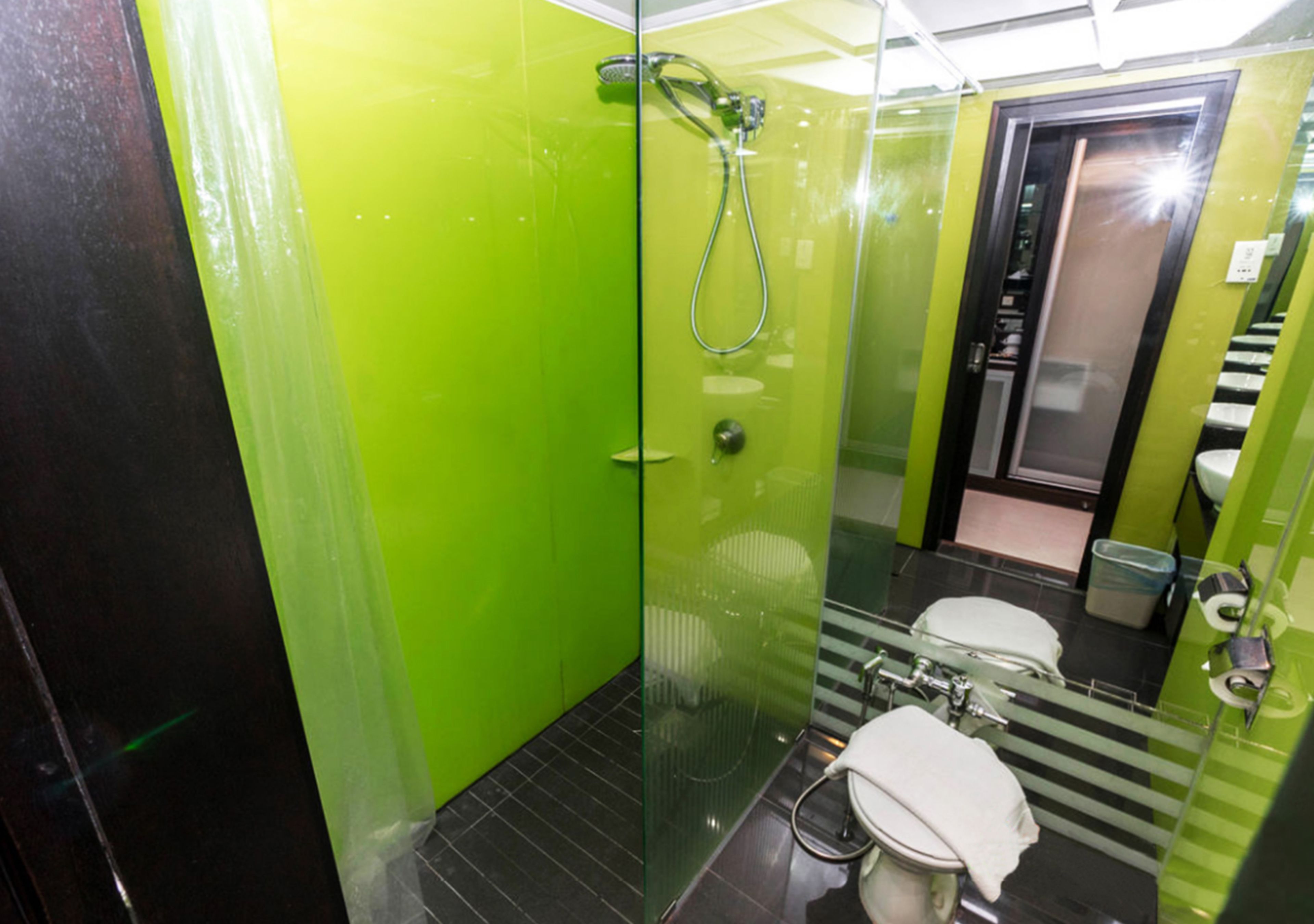 A bathroom with a glass shower enclosure, a toilet, and a sink.