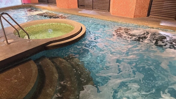 A hot tub with a circular seating area and a pool with visible water movement.