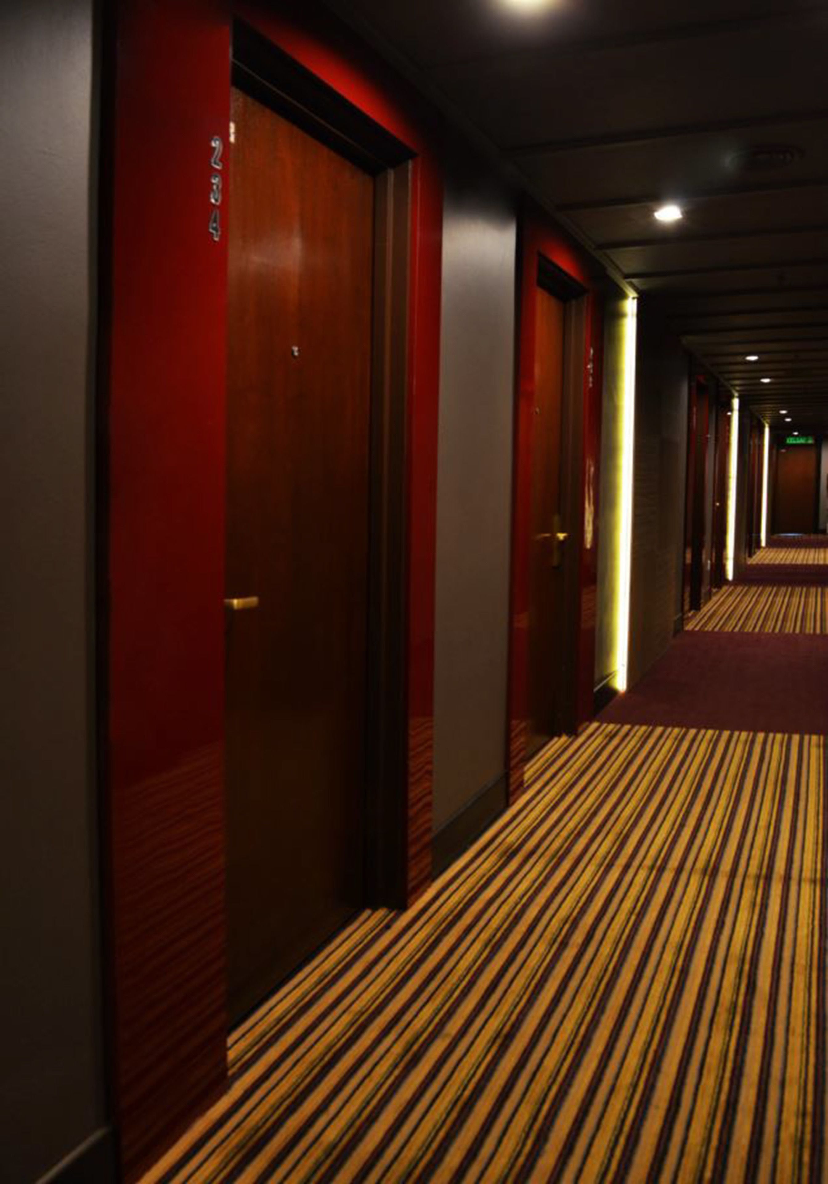Un pasillo de hotel con alfombra a rayas y puertas rojas.