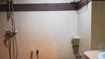 Un baño pequeño con ducha, inodoro y lavamanos.